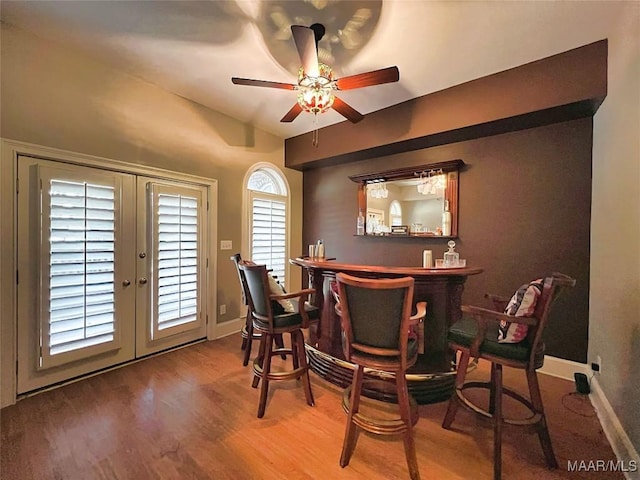 dining space featuring wood-type flooring, french doors, ceiling fan, and indoor bar