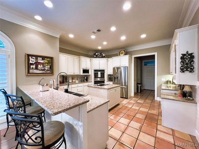 kitchen with sink, appliances with stainless steel finishes, white cabinetry, a center island, and kitchen peninsula