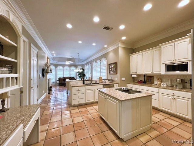 kitchen with appliances with stainless steel finishes, a kitchen island, visible vents, and decorative light fixtures