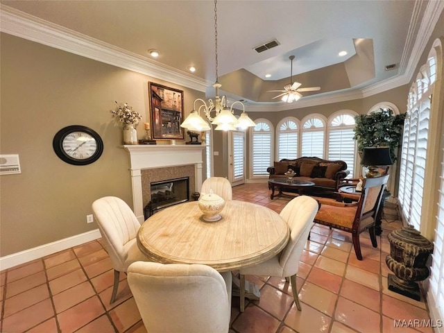 dining space featuring ornamental molding, a glass covered fireplace, visible vents, and a tray ceiling