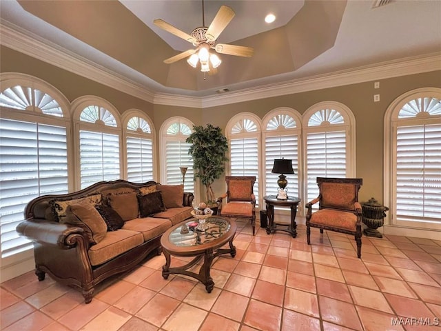 living area featuring light tile patterned floors, ceiling fan, visible vents, ornamental molding, and a raised ceiling