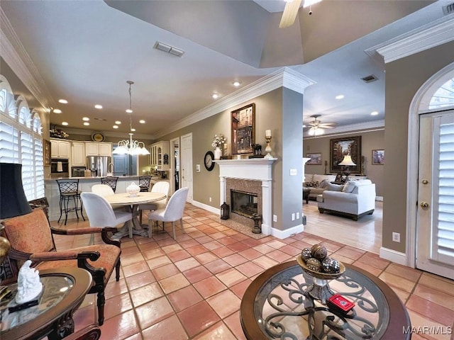 living room featuring light tile patterned flooring, ornamental molding, a healthy amount of sunlight, and ceiling fan with notable chandelier