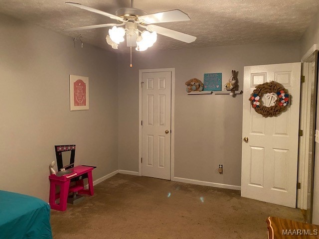 bedroom with ceiling fan, carpet flooring, and a textured ceiling