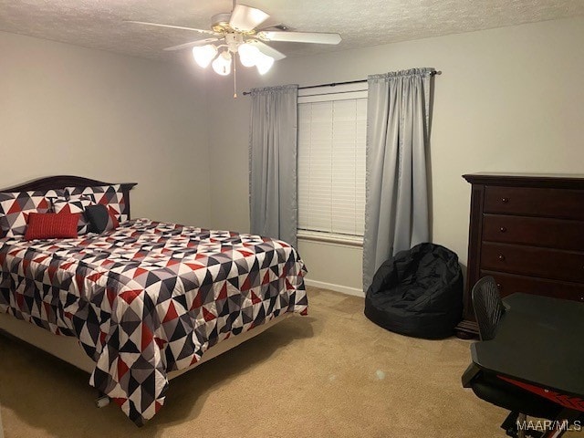 bedroom featuring a textured ceiling, light colored carpet, and ceiling fan