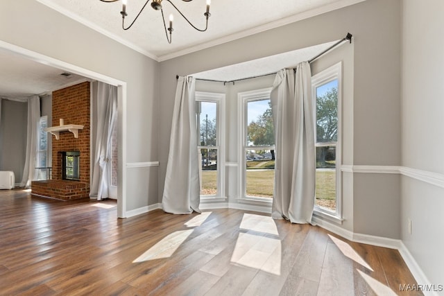 entryway featuring an inviting chandelier, a textured ceiling, hardwood / wood-style flooring, a brick fireplace, and crown molding