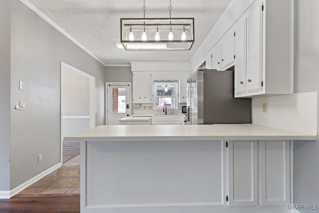 kitchen with stainless steel fridge, white cabinets, and kitchen peninsula