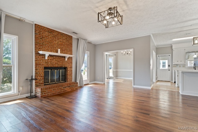 unfurnished living room featuring a wealth of natural light, a textured ceiling, and light hardwood / wood-style floors