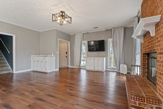 unfurnished living room featuring a textured ceiling, a chandelier, a fireplace, and dark hardwood / wood-style flooring