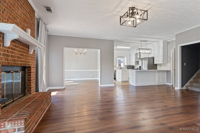 unfurnished living room featuring a textured ceiling, dark hardwood / wood-style flooring, a brick fireplace, brick wall, and ornamental molding