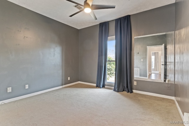 spare room with a textured ceiling, carpet flooring, and ceiling fan