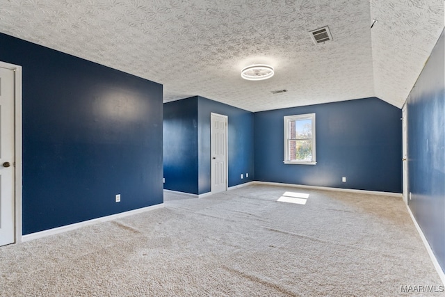 spare room featuring lofted ceiling, carpet, and a textured ceiling