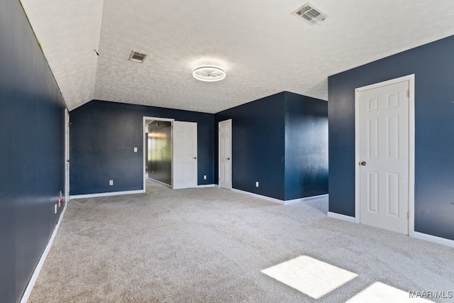 unfurnished bedroom with lofted ceiling, a textured ceiling, and carpet floors