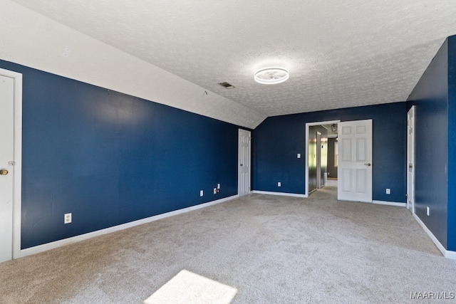 unfurnished bedroom with a textured ceiling, carpet, and vaulted ceiling