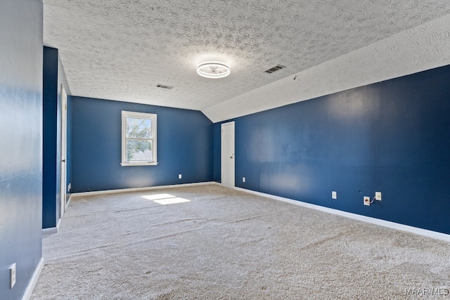 carpeted empty room with a textured ceiling and vaulted ceiling