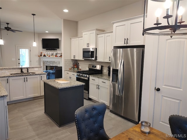 kitchen featuring a center island, white cabinets, sink, light stone countertops, and stainless steel appliances