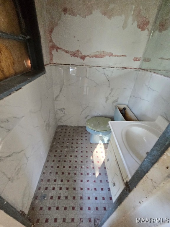 bathroom featuring vanity, toilet, and tile walls