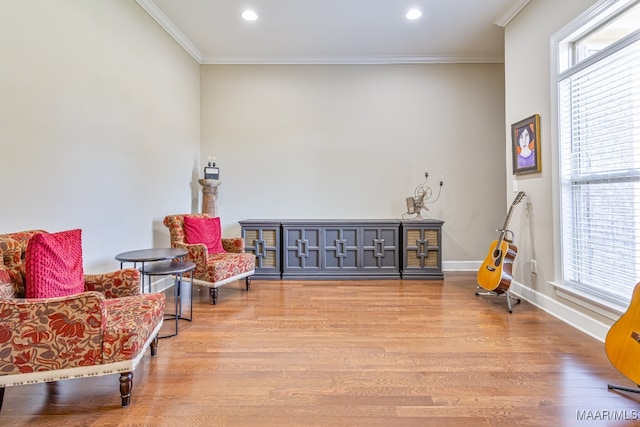 living area featuring light hardwood / wood-style flooring, ornamental molding, and a healthy amount of sunlight