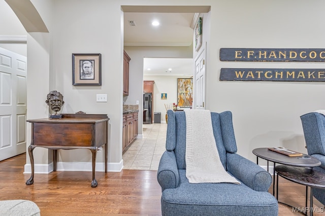 living area with ornamental molding and light hardwood / wood-style flooring