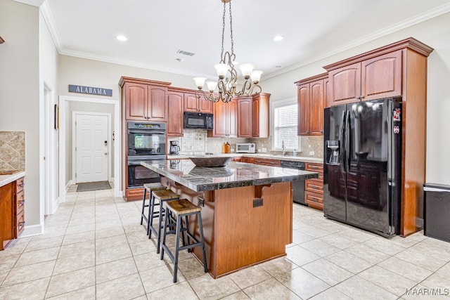 kitchen with black appliances, a kitchen island, a kitchen breakfast bar, ornamental molding, and light tile patterned floors