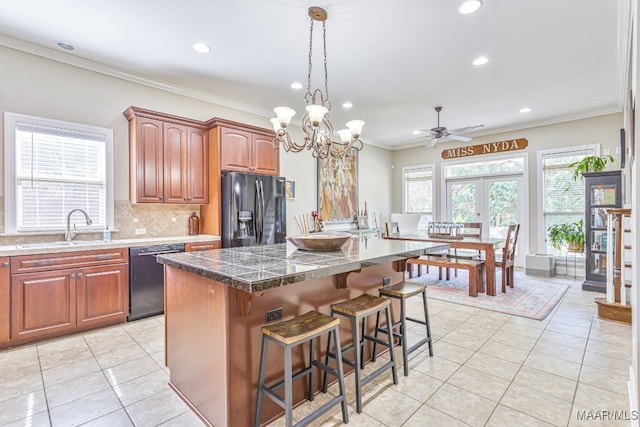 kitchen with black appliances, light tile patterned floors, a wealth of natural light, and a kitchen island