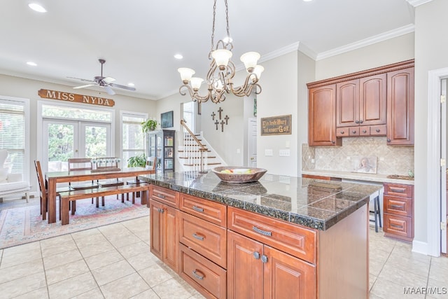 kitchen featuring ornamental molding, a center island, ceiling fan with notable chandelier, and light tile patterned floors