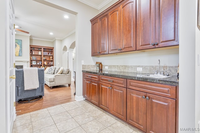 kitchen with sink, decorative columns, ceiling fan, ornamental molding, and light tile patterned floors