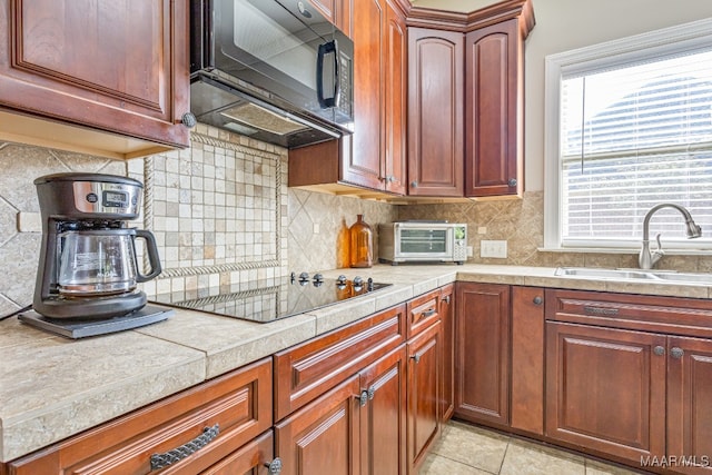 kitchen with backsplash, black appliances, sink, and light tile patterned floors