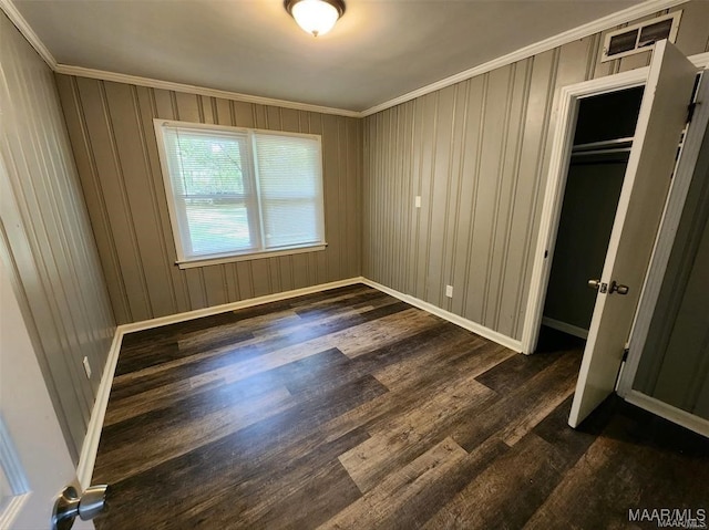 unfurnished bedroom featuring ornamental molding, dark wood-type flooring, and a closet