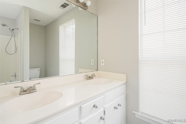 bathroom featuring toilet, walk in shower, and vanity