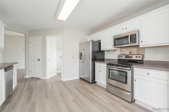 kitchen featuring white cabinets, tasteful backsplash, appliances with stainless steel finishes, a textured ceiling, and light wood-type flooring