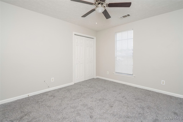 unfurnished bedroom with carpet, a textured ceiling, a closet, and ceiling fan