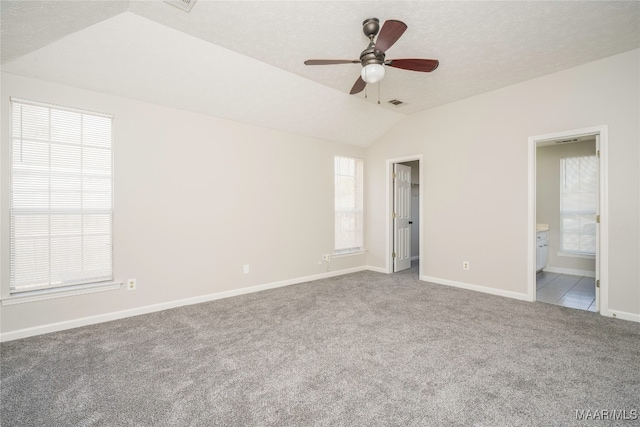 unfurnished room featuring carpet flooring, lofted ceiling, and a wealth of natural light