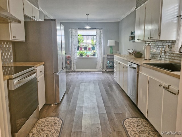 kitchen with appliances with stainless steel finishes, dark hardwood / wood-style flooring, pendant lighting, white cabinets, and exhaust hood