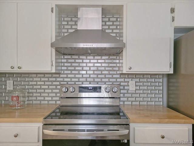 kitchen with wall chimney range hood, decorative backsplash, white cabinetry, and appliances with stainless steel finishes