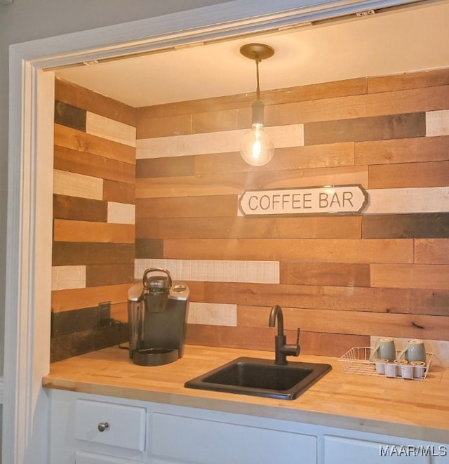 kitchen with sink, butcher block countertops, decorative light fixtures, and white cabinets