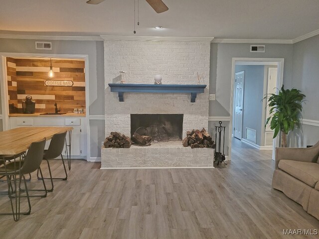 living room with light hardwood / wood-style floors, sink, and a brick fireplace