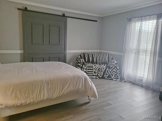 bedroom featuring light hardwood / wood-style floors, ornamental molding, and a barn door