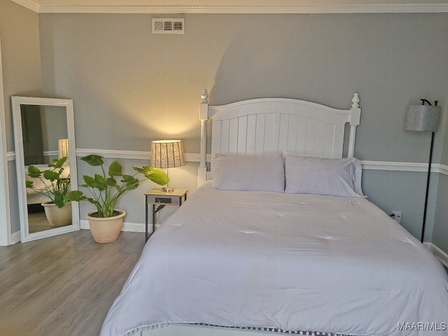 bedroom featuring ornamental molding and hardwood / wood-style flooring