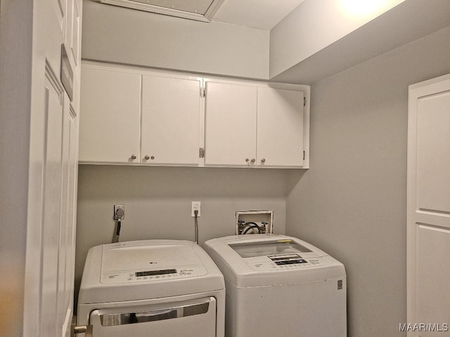 clothes washing area featuring cabinets and washer and clothes dryer