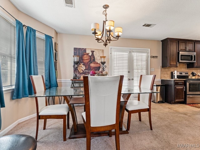 dining room featuring light carpet, a textured ceiling, and a notable chandelier