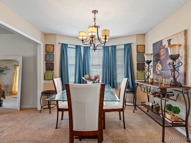 dining area with a chandelier, carpet, and a textured ceiling