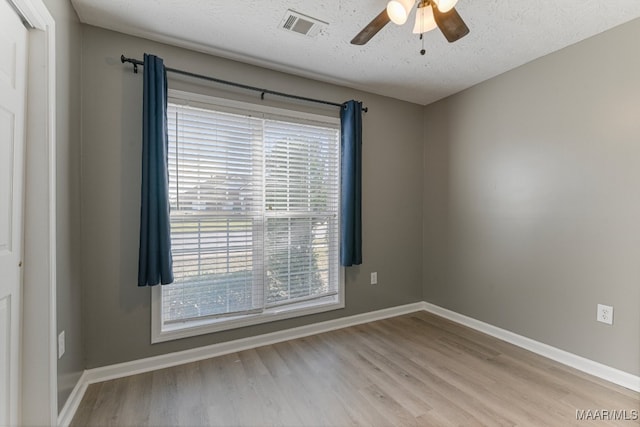 spare room with a textured ceiling, light hardwood / wood-style floors, and ceiling fan