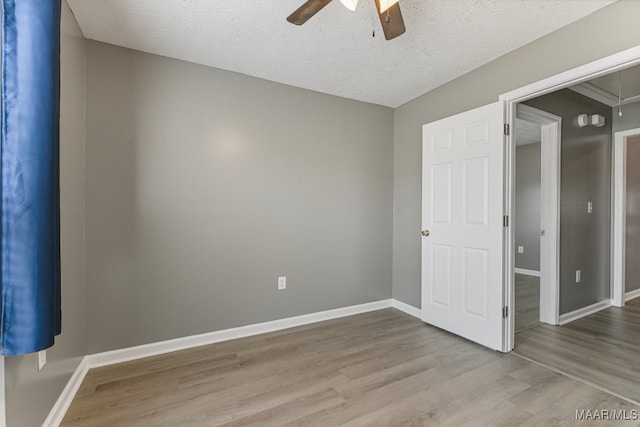 unfurnished bedroom with a textured ceiling, light wood-type flooring, and ceiling fan