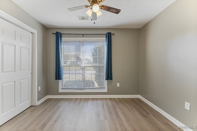 spare room featuring a textured ceiling, light wood-type flooring, and ceiling fan