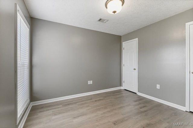 empty room featuring a textured ceiling and light wood-type flooring