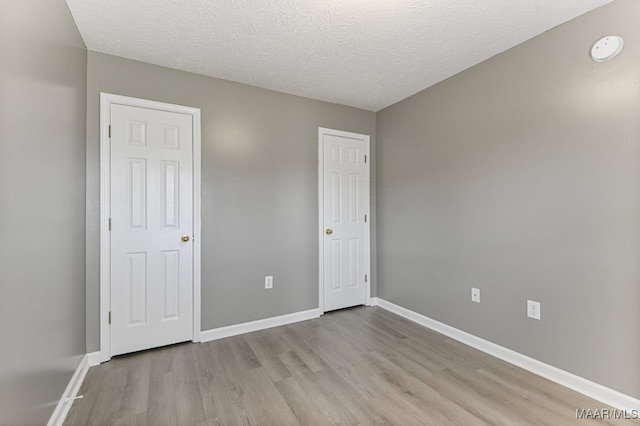 unfurnished bedroom with a textured ceiling and light hardwood / wood-style flooring