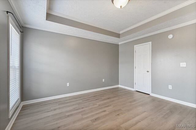 spare room featuring a healthy amount of sunlight, crown molding, a textured ceiling, and light wood-type flooring