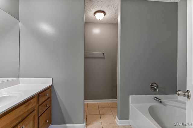 bathroom featuring a bathtub, a textured ceiling, tile patterned flooring, and vanity