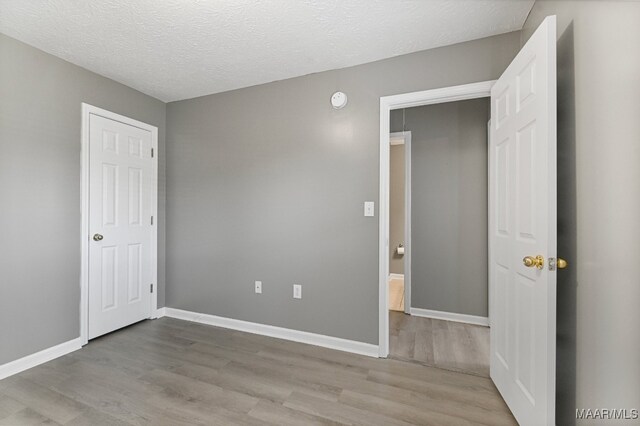 unfurnished bedroom featuring a textured ceiling and light hardwood / wood-style flooring