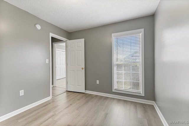 empty room featuring a textured ceiling and light hardwood / wood-style flooring